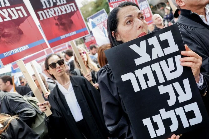 A woman holds a sign with writing in Hebrew reading 