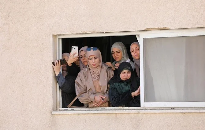 People watch from a window as mourners carry the bodies of Jawad Bawakna and Adham Jabarin during their funeral, Jenin, West Bank, Jan. 19, 2023. (Reuters)