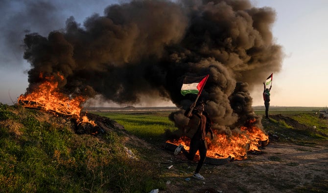 Palestinians burn tires and wave the national flag during a protest against Israeli military raid in the city of Jenin on Thursday, Jan. 26, 2023. (AP)