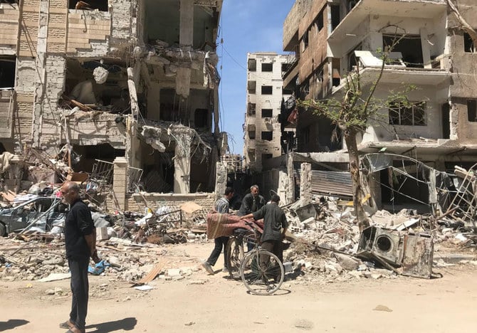 People stand in front of damaged buildings, in the town of Douma, the site of a suspected chemical weapons attack, near Damascus, Syria (AP)