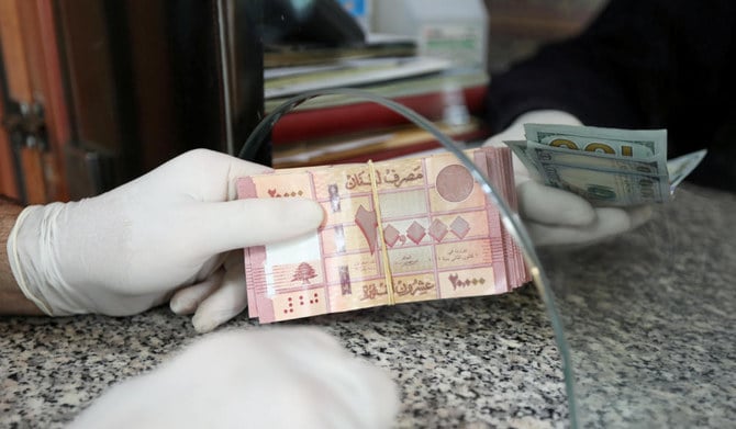 A customer wearing gloves holds Lebanese pounds at a currency exchange store in Beirut. (REUTERS)
