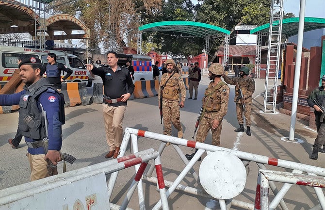 Army soldiers and police officers clear the way for ambulances rushing toward a bomb explosion site, at the main entry gate of police offices, in Peshawar, Pakistan, on January 30, 2023 (AP)