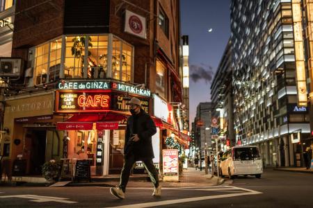 A man crosses a street in Ginza district of Tokyo on January 24, 2023. (AFP)