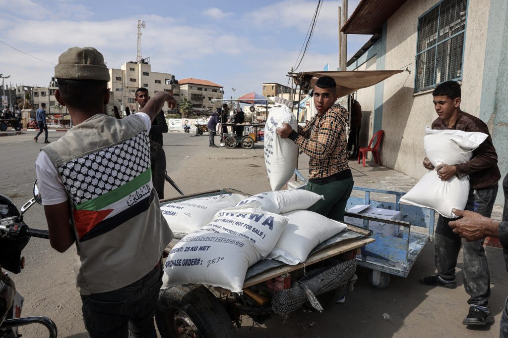 Palestinians carry bags of flour received as aid to poor families, at the United Nations Relief and Works Agency for Palestine Refugees (UNRWA) distribution center, in the Rafah refugee camp in the southern Gaza Strip, on January 22, 2023. (AFP)