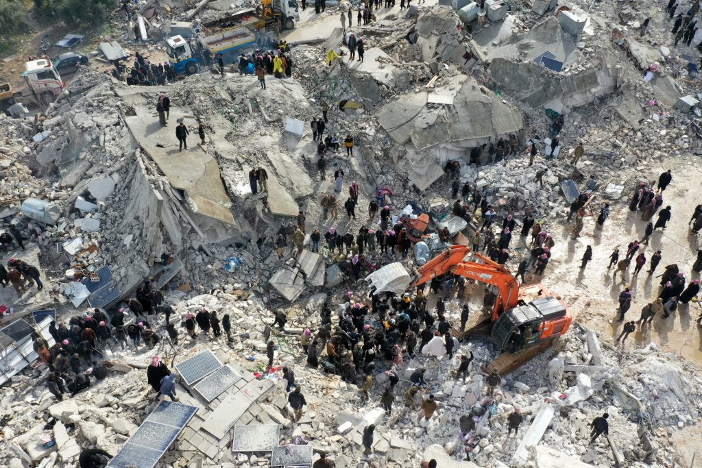 This aerial view shows residents, aided by heavy equipment, searching for victims and survivors amidst the rubble of collapsed buildings following an earthquake in the village of Besnia near the town of Harim, in Syria's rebel-held noryhwestern Idlib province on the border with Turkey, on February 6, 2022. (AFP)