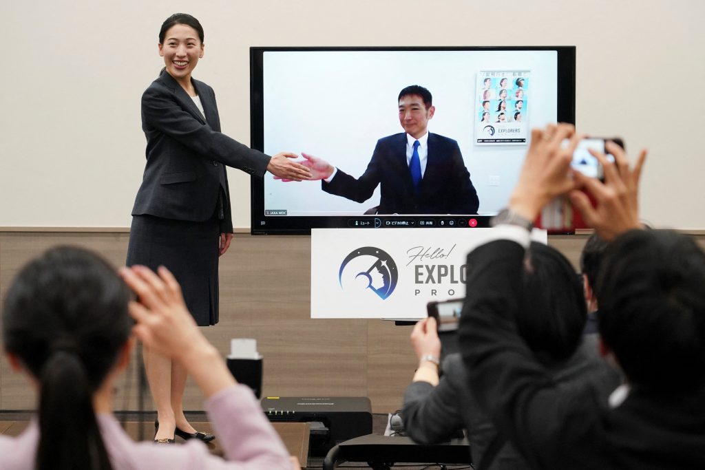 Astronaut candidates for the Japan Aerospace Exploration Agency (JAXA), Ayu Yoneda (L), a surgeon at the Japanese Red Cross Medical Center, and Makoto Suwa (on screen), a disaster prevention specialist at the World Bank, pose after a press conference in Tokyo on February 28, 2023. (AFP)