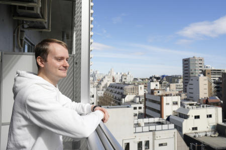 Ukrainian Dmytro Remez looks at the neighborhoods from the balcony of his dormitory room in Tokyo, on Feb. 15, 2023. (AP)