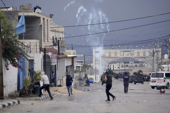 Palestinians run from tear gas fired by Israeli forces raiding Aqbat Jabr camp, southwest of the city of Jericho on Saturday, Feb. 4, 2023. (AP)
