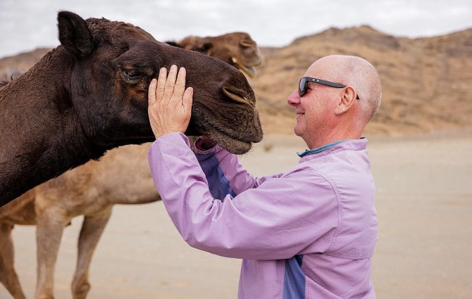 Mark Evans playfully embraces a camel in one of the villages and farms of Quwayiah on the second leg of the Heart of Arabia expedition. (Photo/Ana-Maria Pavalache)