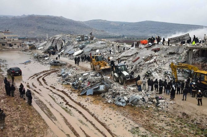 This aerial view shows residents helped by bulldozers, searching for victims and survivors in the rubble of collapsed buildings, following an earthquake in the town of Sarmada in the countryside of the northwestern Syrian Idlib province, early on February 6, 2023. (AFP)