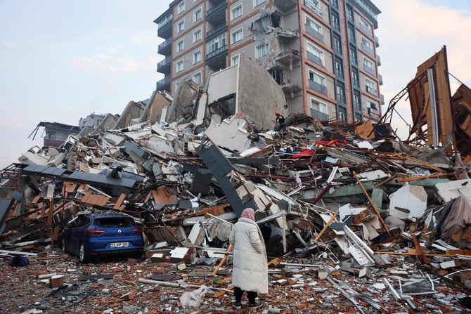 A woman looks on as rescuers search for survivors under the rubble following an earthquake in Hatay, Turkiye. (Reuters)