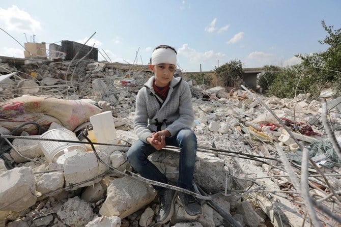 A Syrian boy, who lost his family as a result of the quake that hit Turkey and Syria, sits amid the rubble of his family home in the town of Jindayris, Aleppo. (File/AFP)