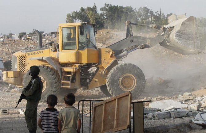 An Israeli bulldozer destroys the Palestinian homes and a community centre in southern West Bank, near the Israeli settlement of Karmel. (File/AFP)