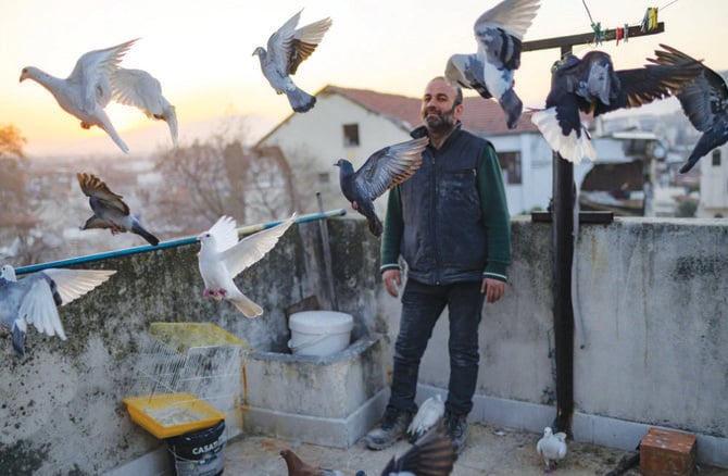 Murat Guzel scatters bird food on the roof of a restaurant where he worked before the earthquake in Antakya. (AFP)