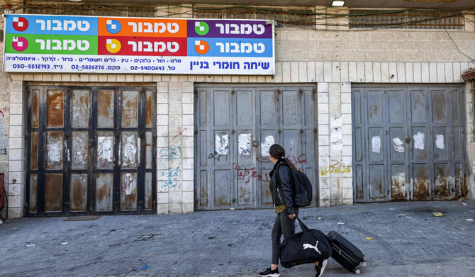 A woman walks past shops that are closed as part of a declared general strike by Palestinians against house demolitions carried out by Israeli authorities, in the east Jerusalem neighbourhood of Issawiya on February 19, 2023. (AFP)