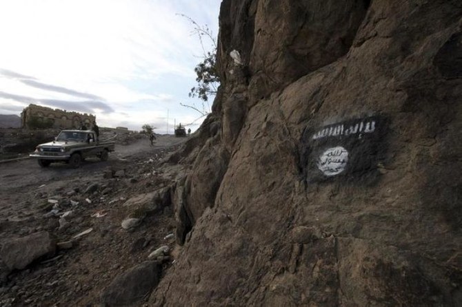 Houthi militia drive a truck past an Al-Qaeda flag, painted on the side of a hill, along a road in Almnash, Rada’a District, Al Bayda Governorate, Yemen, Nov. 22, 2014. (Reuters)
