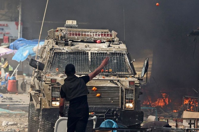 A Palestinian faces an Israeli military vehicle during a raid on the occupied-West Bank city of Nablus, on February 22, 2023. (AFP)