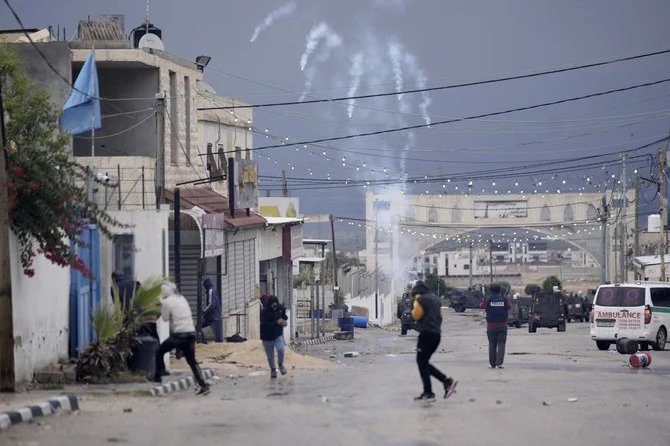 Palestinians run from tear gas fired by Israeli forces raiding Aqbat Jabr camp, southwest of the city of Jericho on Saturday, Feb. 4, 2023. (AP)
