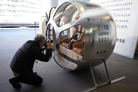 A journalist photographs a two-seater cabin that a startup company says is capable of rising to an altitude of 15 miles, which is roughly the middle of the stratosphere, is displayed during a news conference in Tokyo, Tuesday, Feb. 21, 2023. (AP)