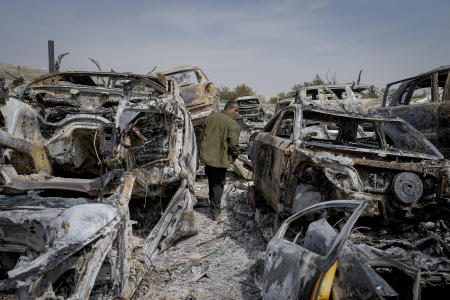 A Palestinian man walks between scorched cars in a scrapyard, in the town of Hawara, near the West Bank city of Nablus, Monday, Feb. 27, 2023. (AP)