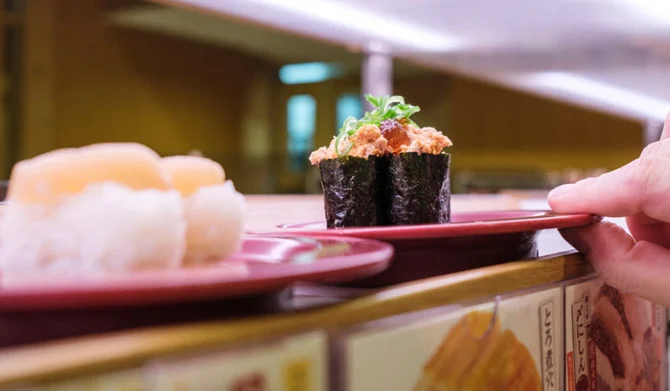 This picture shows plates of sushi on a conveyor belt at a sushi chain restaurant in Tokyo on February 3, 2023. (AFP)