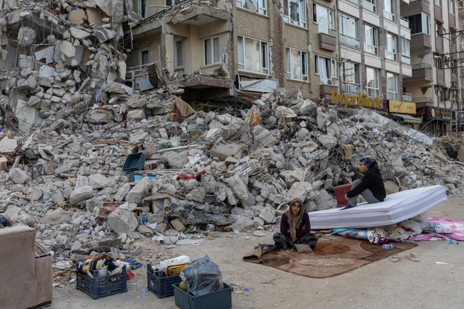 Perihan Fansa and Ayfer Sarac sit outside a destroyed building while waiting for their brother to take furniture out of his apartment in the aftermath of the deadly earthquake in Antakya, Hatay province on Feb. 20, 2023. (Reuters)