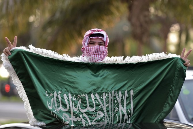 A Saudi football fan waves their country's flag from the skylight window of a car in Riyadh amidst celebrations of Saudi Arabia's win over Argentina in the Qatar 2022 World Cup, in the capital Riyadh on Nov. 22, 2022. (AFP)