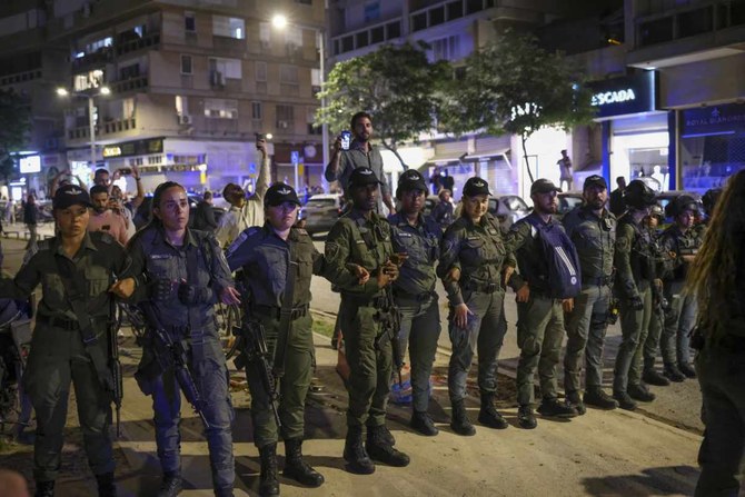 Police stand guard outside a Tel Aviv salon where protesters demonstrating against the government's planned judicial overhaul amassed on March 1, 2023, after learning that the prime minister's wife, Sara Netanyahu, was getting her hair done inside. (AP Photo/Oren Ziv)
