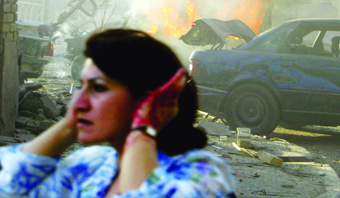 An injured Iraqi woman flees the site of two car bombs that exploded in quick succession near two Baghdad churches on Aug. 1, 2004. (AFP)