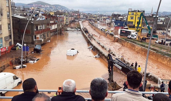 Standing at a high point, people look down at submerged cars, destroyed infrastructure, ferocity of floodwater and efforts to ease the situation in Sanliurfa, southeastern Turkiye, on Wednesday. (AFP)