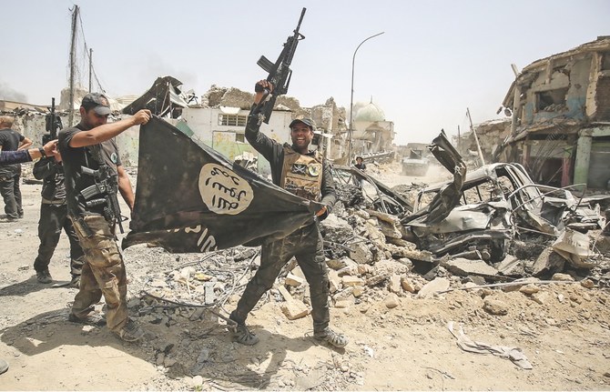 Members of the Iraqi Counter-Terrorism Service cheer as they carry upside-down the black flag of Daesh, with the destroyed Al-Nuri mosque seen in the background, in the Old City of Mosul on July 2, 2017. (AFP)