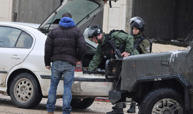 Israeli soldiers search a car at a checkpoint in the Palestinan town of Huwara in the occupied West Bank following a shooting attack on an Israeli settler’s car. (AFP)