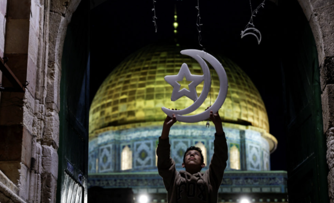 A Palestinian man hangs decorations at an entrance to the compound known to Muslims as the Noble Sanctuary and to Jews as the Temple Mount, ahead of the holy fasting month of Ramadan in Jerusalem's Old City, March 20, 2023. (Reuters)