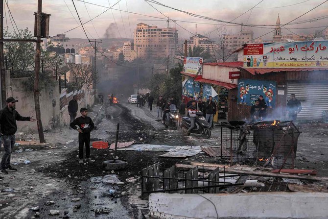 People inspect debris along a road during an Israeli army raid in the Jenin camp for Palestinian refugees in the occupied West Bank on March 7, 2023. (AFP)