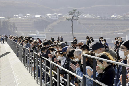 People observe a moment of silence at 2:46 p.m., the moment the earthquake struck in Rikuzentakata, Iwate prefecture on Saturday, March 11, 2023. (Kyodo News via AP)