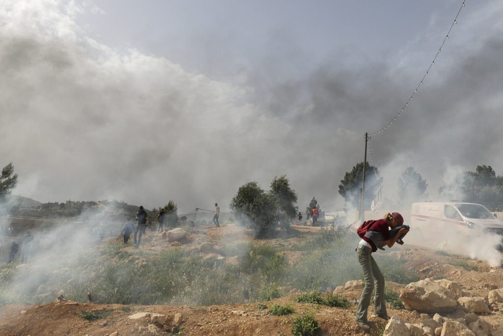 Palestinian protesters rush away from tear gas amid clashes with Israeli security forces during a protest in the village of Beita, south of Nablus in the occupied West Bank, on April 10, 2023, against a march by settlers to the nearby Israeli outpost of Eviatar. (AFP)