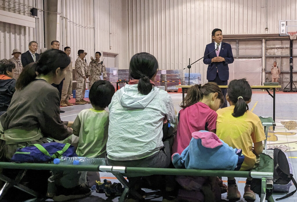 This handout photo taken on April 24, 2023 and released by Foreign Ministry of Japan on April 25 shows senior Vice Foreign Minister TAKEI Shunsuke (top) welcoming Japanese nationals who have been evacuated from Sudan in Djibouti. (AFP)