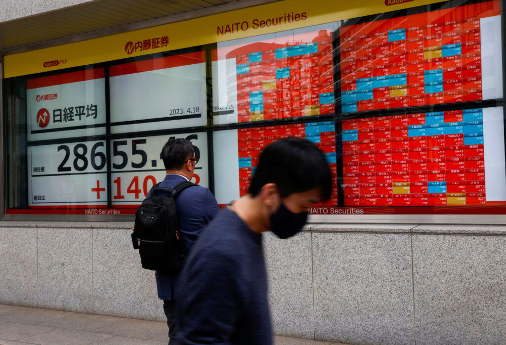 Passersby walk past an electric board displaying Japan's Nikkei share average outside a brokerage in Tokyo. (File/Reuters)