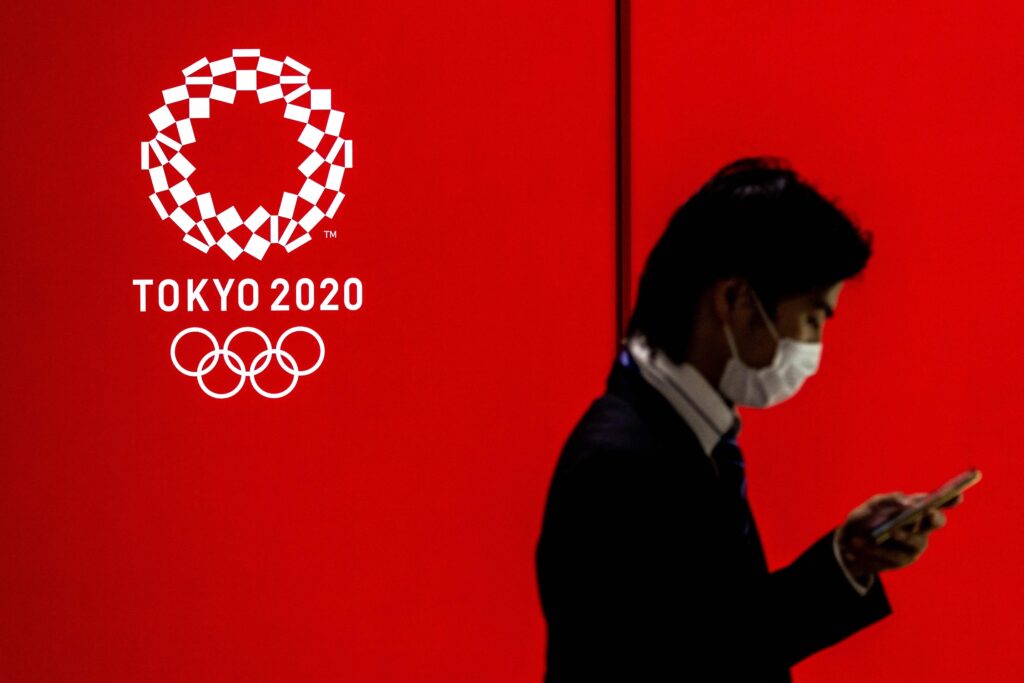 This file photo taken on July 15, 2021 shows a man walking past a logo of the Tokyo 2020 Olympic Games in Tokyo on July 15, 2021. The former chairman of a Tokyo 2020 Olympics sponsor was handed a suspended prison sentence on April 21, 2023, along with two others, in the first convictions in a spiralling bribery scandal surrounding the Games. (AFP)