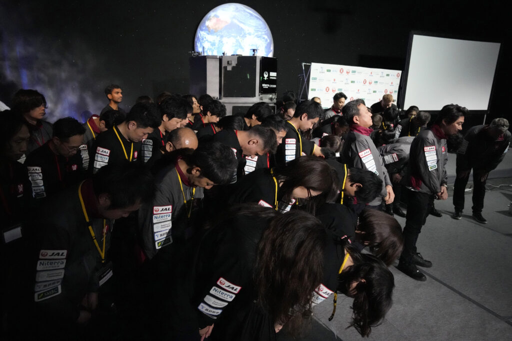 Takeshi Hakamada, founder and CEO of ispace, right, and his team staff bow at the end of livestream of HAKUTO-R private lunar exploration program on screen at the lunar landing event Wednesday, April 26, 2023, at Miraikan, the National Museum of Emerging Science and Innovation, in Tokyo. (File/AP Photo)