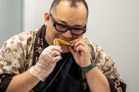 This picture taken on March 4, 2023 shows Japan Karaage Assosiation executive director Kouichirou Yagi eating a chicken wing during the Karaage Grand Prix competition in Tokyo. (AFP) 