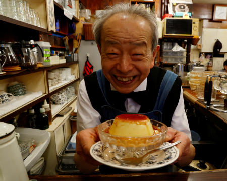 Shizuo Mori poses with a pudding during a photo opportunity at his Heckeln coffee shop in Tokyo, March 15, 2023. (Reuters)