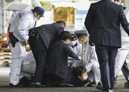 A man believed to be a suspect, on the ground, is caught by police after he allegedly threw a suspicious object as Japanese Prime Minister Fumio Kishida visited Saikazaki port for an election campaign event in Wakayama, western Japan, on Saturday. (Kyodo News via AP)