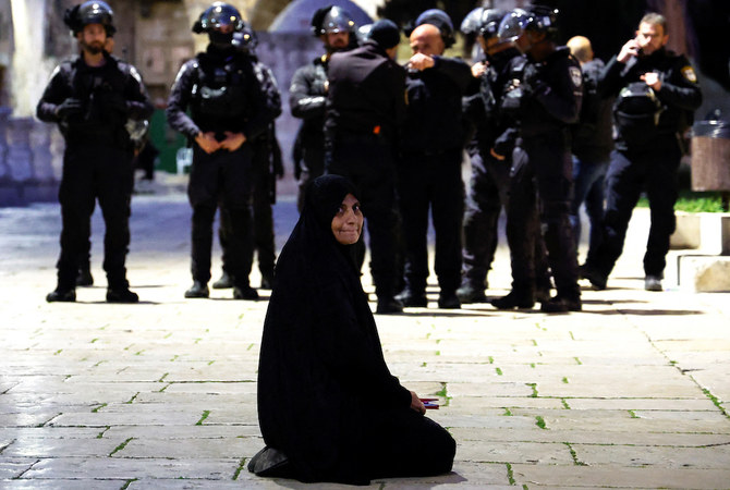 A Palestinian woman sits near Israeli border policemen in the Al-Aqsa compound, also known to Jews as the Temple Mount, while tension arises during clashes with Palestinians in Jerusalem’s Old City on April 5, 2023. (Reuters)