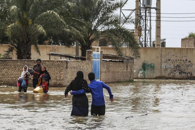 An Iranian family walks through a flooded street in a village around the city of Ahvaz, in Iran's Khuzestan province, in March 2019. (AFP/File)