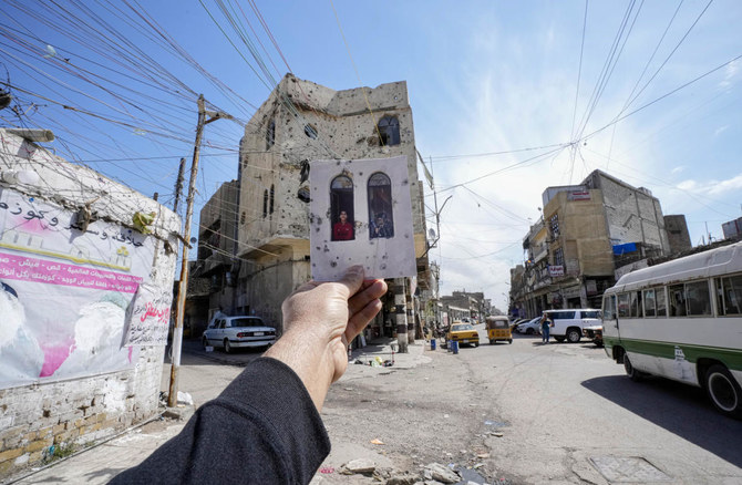 A photograph of Mohhamed, left, and Adil Omar, who lost their father in sectarian violence, looking out of their home in predominantly Sunni neighborhood of Fadhil in Baghdad, 20 years after the U.S. led invasion on Iraq and subsequent war. (AP)