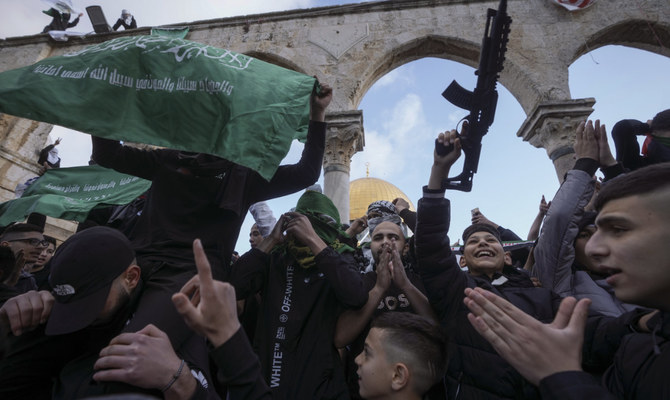 Palestinians brandish a toy gun and wave the flag of the Hamas militant group in protest against Israel, during Eid Al-Fitr holiday celebrations by the Dome of the Rock shrine in the Al Aqsa Mosque compound in Jerusalem's Old City, Friday, April 21, 2023. (AP)