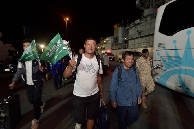 Chinese nationals evacuated from Sudan wave Saudi flags as they arrive at King Faisal navy base in Jeddah on April 26, 2023. (AFP)