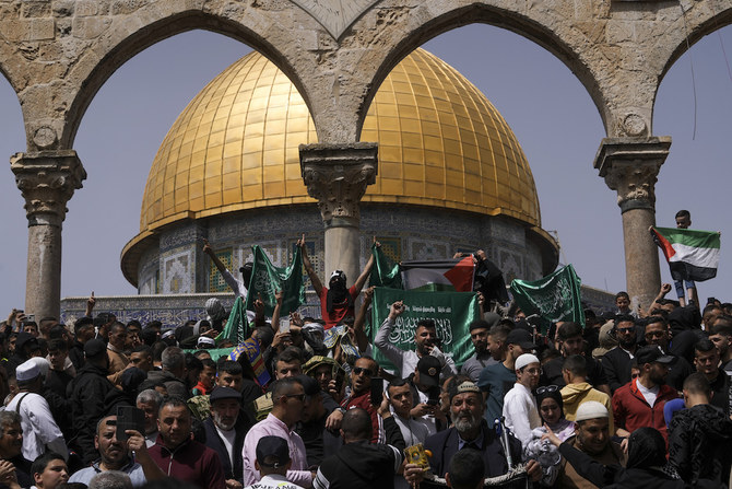 Palestinians hold the Palestinian national flag and the flag of the Hamas militant group during a protest by the Dome of Rock at the Al-Aqsa Mosque compound. (AP)