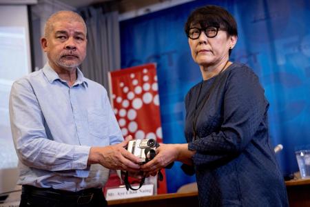 Noriko Ogawa, sister of the late Japanese journalist Kenji Nagai, who was shot dead in Yangon, Myanmar while covering the Saffron Revolution in 2007, receives his camera and footage from journalist Aye Chan Naing (L) at the Foreign Correspondents' Club of Thailand in Bangkok on April 26, 2023. (AFP)